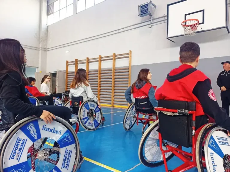 Niños subidos en sillas de ruedas practican deporte en un gimnasio